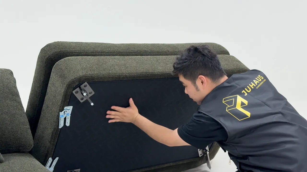 Person in a Juhaus vest examining a sofa mechanism