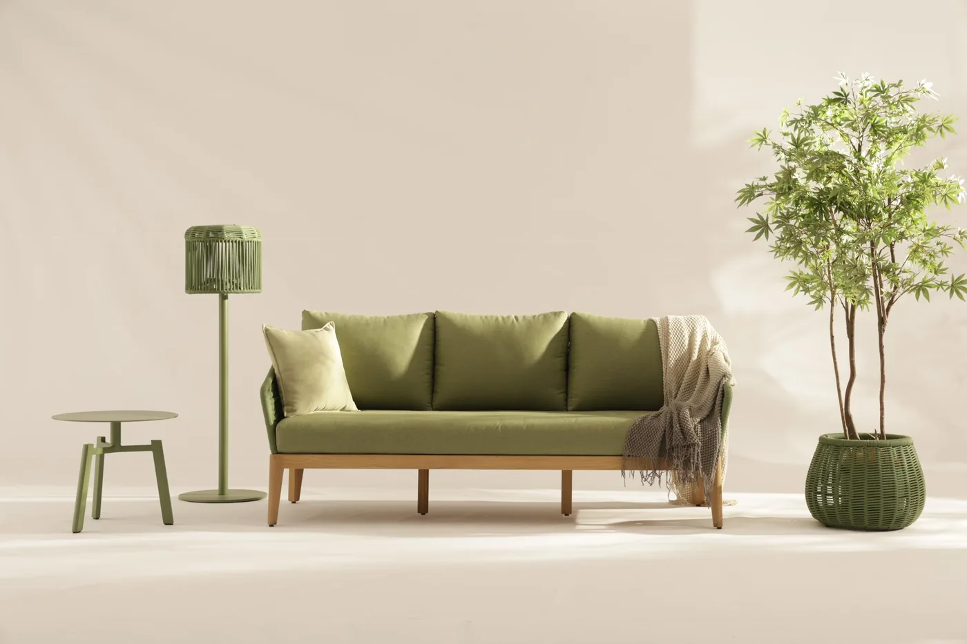 A green woven outdoor lounge set with green upholstered cushions and a small round table.