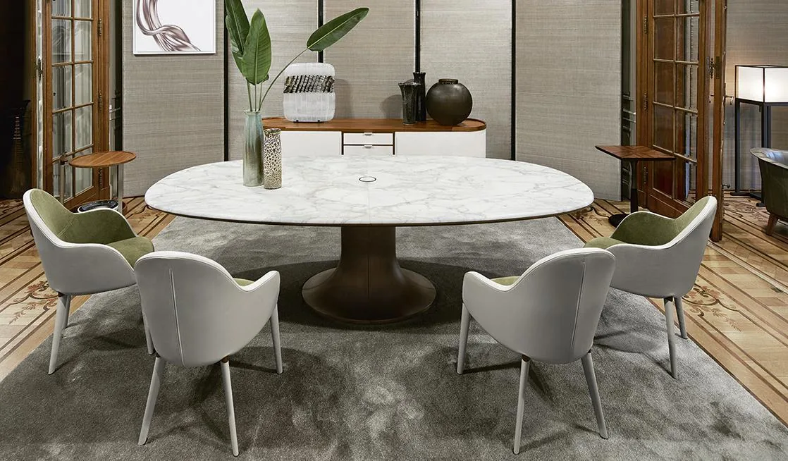 A pale round dining table with upholstered chairs in a bright dining setting.