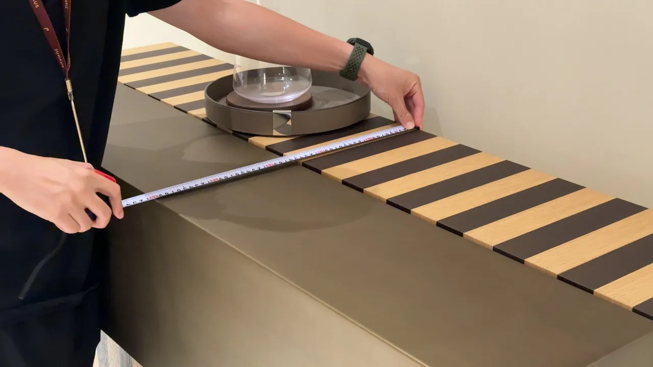Hands checking a furniture surface with a tape measure