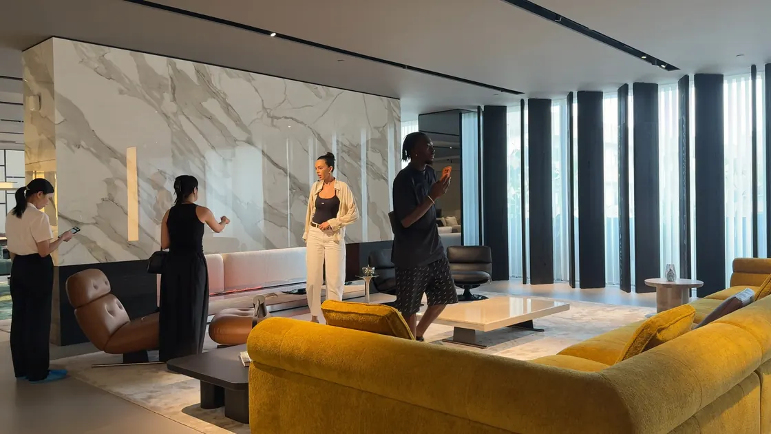Four adults stand among sofas and chairs in a bright showroom.