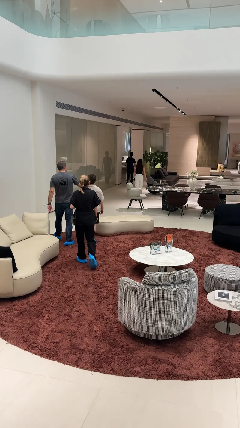 A group walks through a showroom containing sofas, lounge chairs and coffee tables.